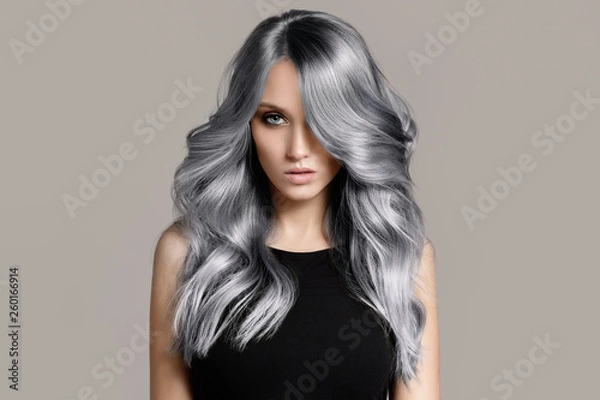 Obraz Piękna kobieta z długie falowane włosy farbujące. Płaskie szare tło.