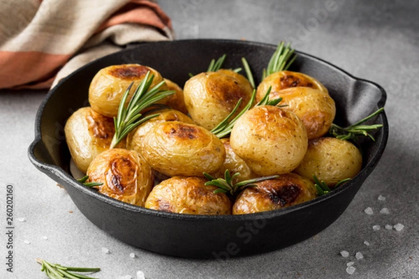 Fototapeta Fried (baked) whole small potatoes with rosemary and salt in a frying pan, ruddy crust, appetizing food