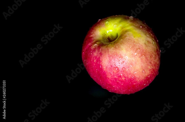Fototapeta Water droplet on glossy surface of red apple on black background