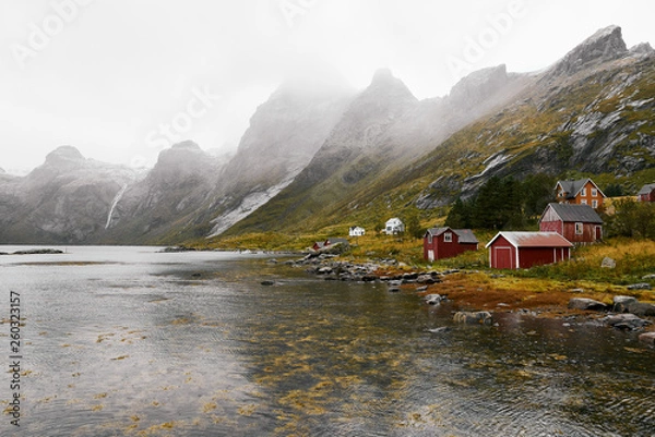 Obraz Panoramic view of a remote old fishing village at the coast in Vinstad with mountains in the background on Lofoten Islands in Norway.