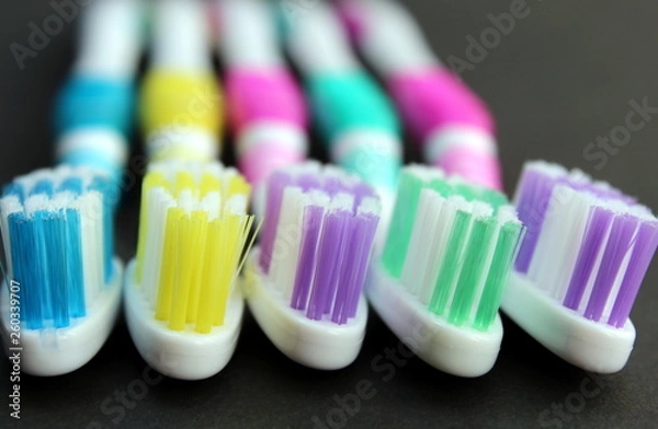 Fototapeta Multi-colored toothbrushes lie on a black background