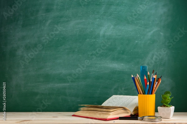 Fototapeta Education and reading concept - group of colorful books on the wooden table in the classroom, blackboard background