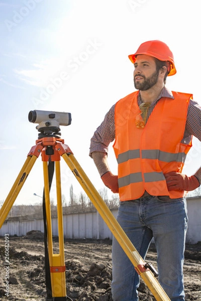 Fototapeta male surveyor engineer with a device working on a construction site in a helmet
