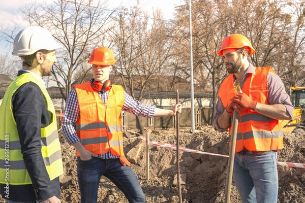Fototapeta male workers engineers in helmets with the head, work, in the hands of a shovel
