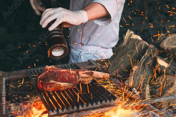 Obraz Chef pepper the steak on fire.