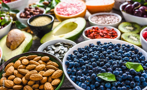 Obraz Bowl with almonds, bilberry, fresh fruit and other healthy food. Organic breakfast with vegetarian nutrition. Super foods collection on table.