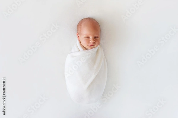 Obraz Newborn baby sleeps in white winding on a white background