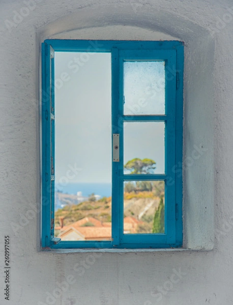 Fototapeta View of the city from the window of the building in the fortress of the old bar, Montenegro. Blue old window among white walls. Summer.