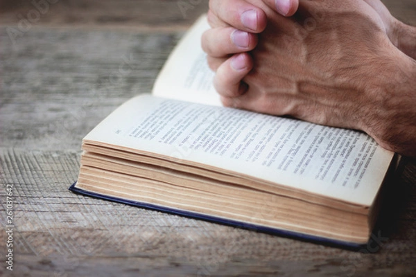 Obraz praying hands over a holy bible
