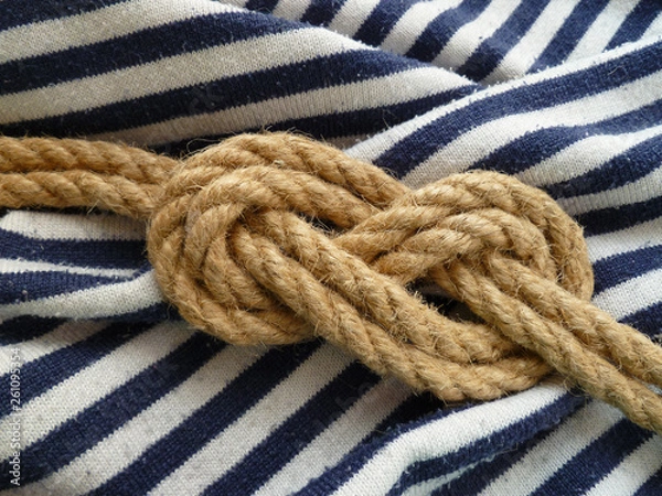 Obraz Double figure eight rope knot isolated on a striped blue white nautical shirt background. Flamand knot.