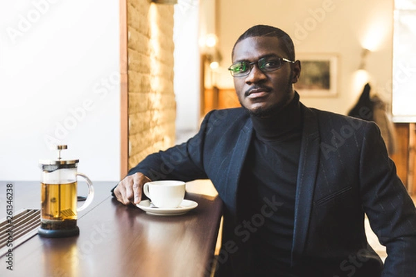 Fototapeta Young handsome dark-skinned businessman in a cafe with a cup of tea.
