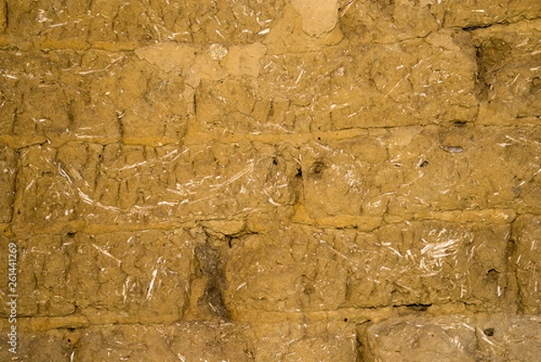 Fototapeta Adobe brick wall with worn-off plaster
