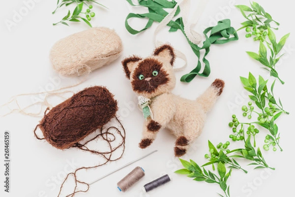 Fototapeta knitted siamese cat on a white background