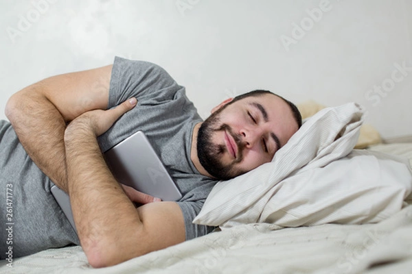Obraz Young and beautiful man sleeps with a tablet in his arms.