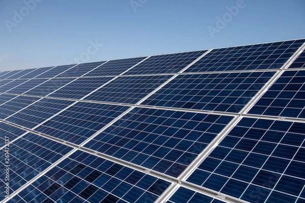 Fototapeta Close up clean solar panels on blue clear sky background producing friendly environment energy. Alternative electricity source