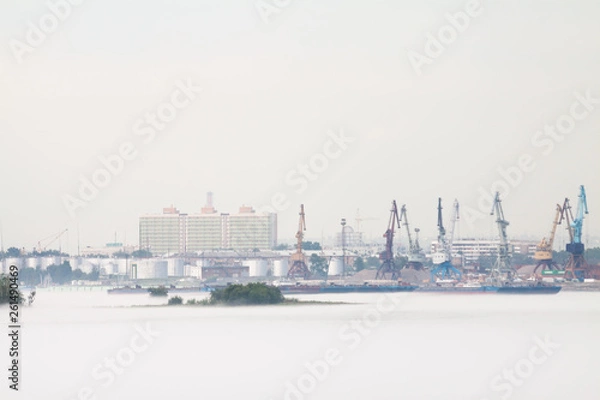 Obraz Cranes and industrial barges in the port, against a background of cloudy weather with fog in the summer. Russia, Krasnoyarsk.