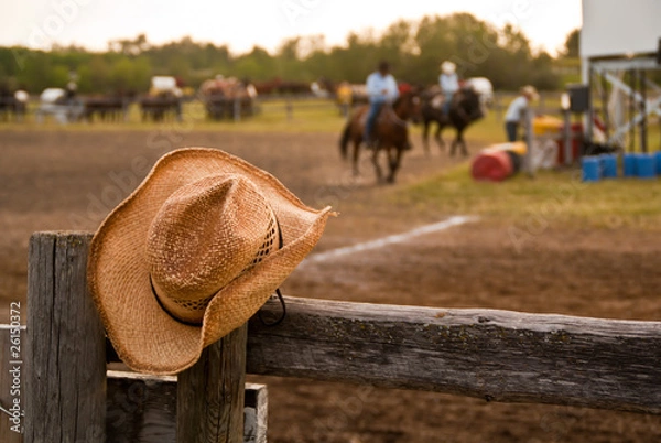 Fototapeta Kowbojski kapelusz wisiał na płocie podczas rodeo z końmi i jeźdźcami