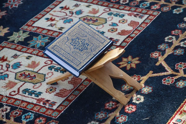 Obraz pięknie oprawiony koran leżacy na pulpicie i dywaniku modlitewnym