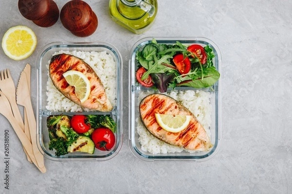 Fototapeta Meal prep containers with salmon and rice, green salad and baked vegetables.