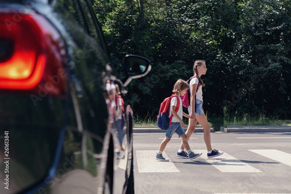 Fototapeta Dzieci obok samochodu przechodzącego przez przejście dla pieszych do szkoły