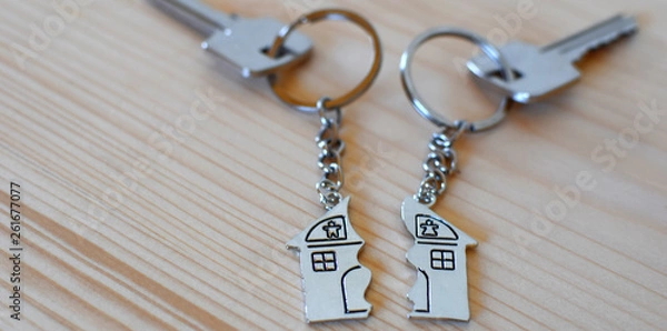 Obraz Two keys with splitted or broken key rings with pendant in shape of house divided in two parts on wooden background with copy space. Dividing house when divorce, division of property, real estate heri