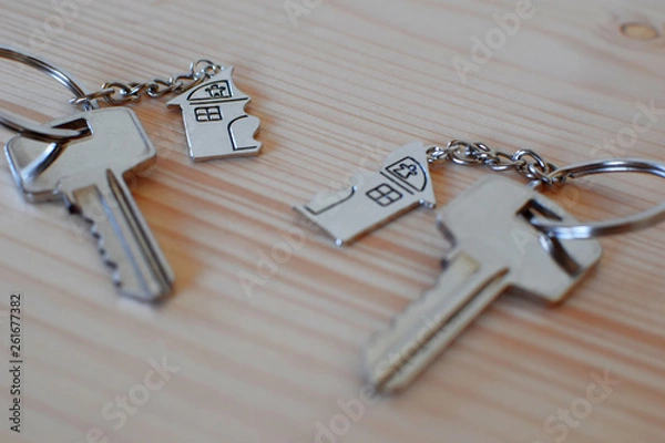 Obraz Two keys with splitted or broken key rings with pendant in shape of house divided in two parts on wooden background with copy space. Dividing house when divorce, division of property, real estate heri