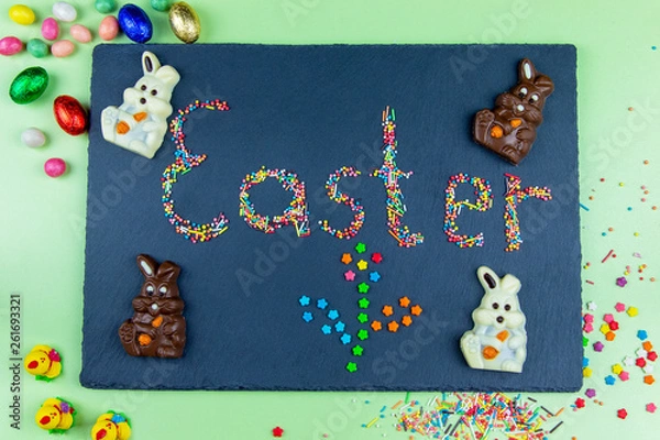 Fototapeta Easter concept multicolored candies are laid out in the form of Easter on a dark blue background with chocolate bunny and eggs