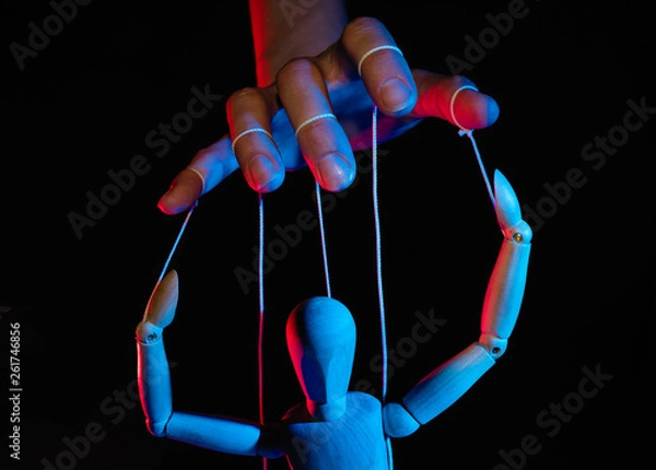 Fototapeta Pojęcie kontroli. Marionetka w ludzkiej dłoni. Obiekty są barwione na czerwono i niebiesko.