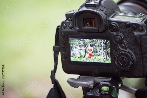 Fototapeta asian beauty vlogger review tutorial vlog viralclip on live streaming and behind cameraman Video or professional digital mirrorless setting on tripod for camera recording at outdoor