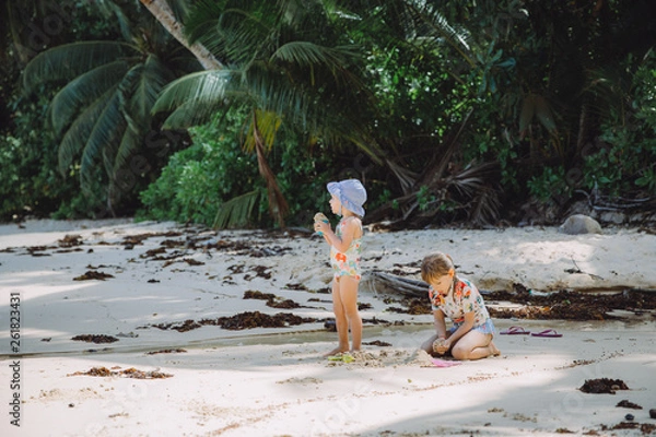 Obraz Two little sisters playing with the sand on the beach