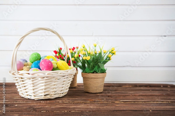 Fototapeta Easter eggs in basket on shelf in front of wooden wall. View with copy space