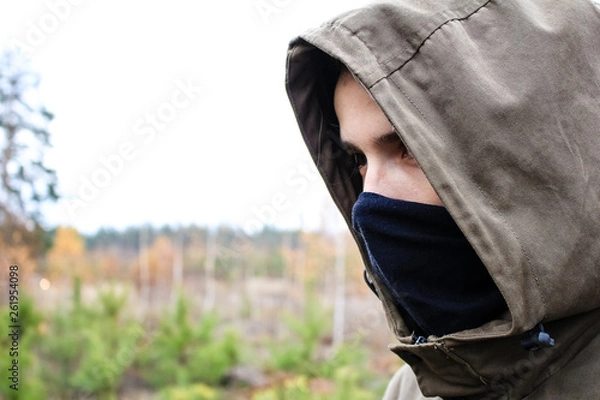 Fototapeta face of a guy in a black mask and hood close up