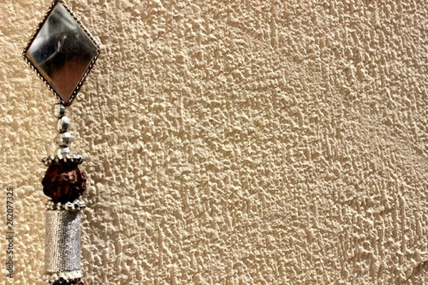 Obraz Decorative pendant object with beads, seeds and mirrors in contrast with beige textured wall composing the decoration of a house in the city of São Paulo, Brazil.