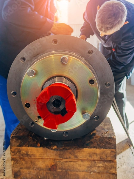 Fototapeta Worker assembles machine part in a factory