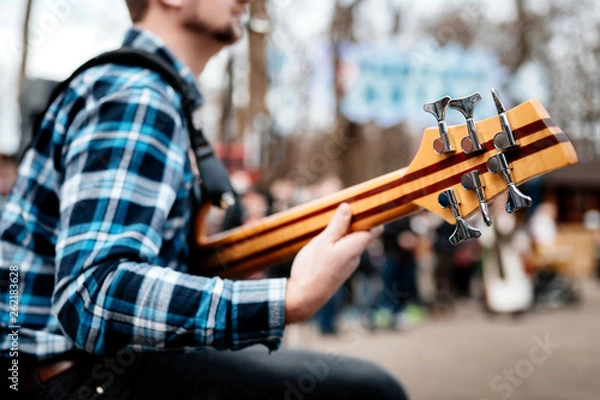 Fototapeta Photo of musician playng on six string fretless bass guitar on the street in front of people.