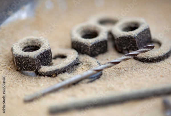 Fototapeta Macro photography of a drill and some nuts and packing rings covered in saw dust, captured at a carpenter workshop in the Andean mountains of central Colombia.