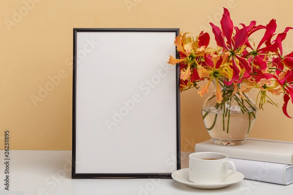 Obraz Composition from a decorative wooden frame and red and yellow flowers of Glorios in a glass vase on a white shelf on a yellow background