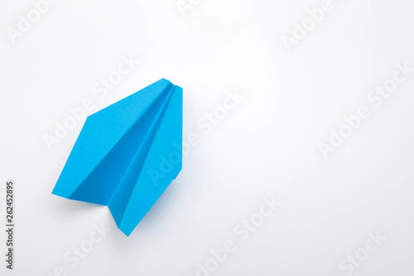 Fototapeta Flat lay of blue paper plane on white background with text space.