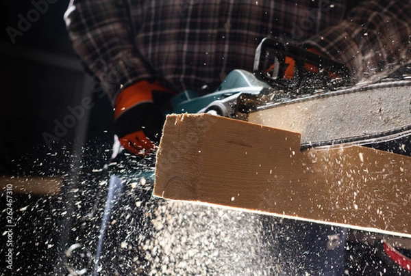 Obraz Man using modern electric circular saw in the workshop
