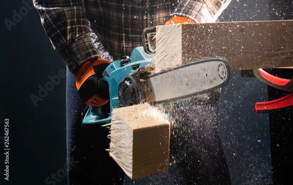 Obraz Man using modern electric circular saw in the workshop
