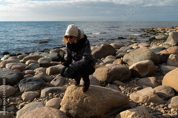 Fototapeta Young archaeologist on a boulder beach looking for exotic rocks on a coastline of a Baltic Sea