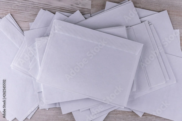 Fototapeta outgoing correspondence: few empty white envelopes on a wooden desk in the office, low contrast