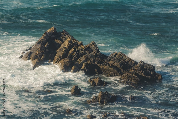 Fototapeta Waves crashing on the rock on the beach