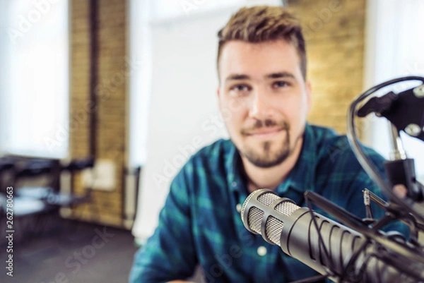Fototapeta Attractive Young Man speaking Into Microphone. Man and podcast host Talking to Microphone.