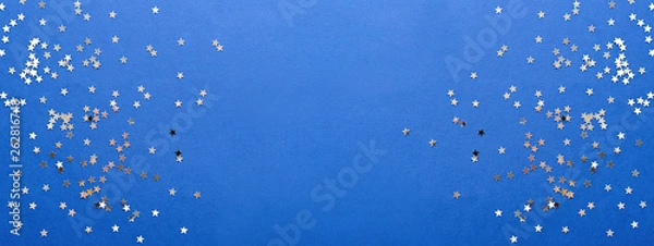 Fototapeta Holiday background with silver star confetti on blue background. Good backdrop for Christmas and New Year cards.