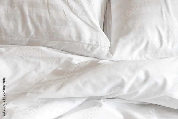Fototapeta white pillow with messy messy blanket on bed in bedroom Close up of bedding sheets with copy space.