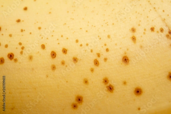 Fototapeta A close-up or macro shot of the overripe yellow skin with pock marks of a banana fruit.