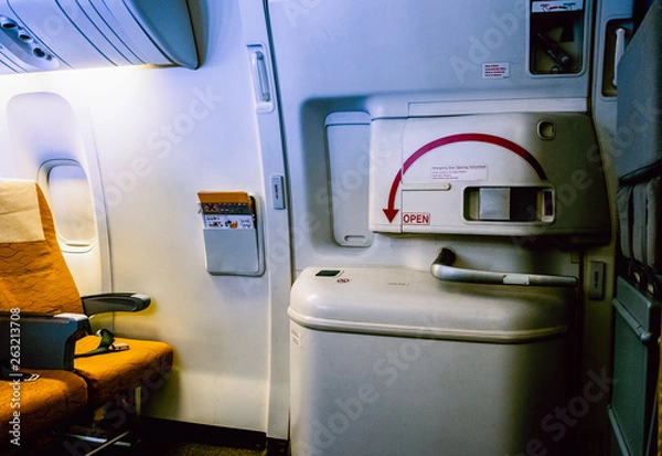 Fototapeta Aircraft interrior with the airplane's entrance, the flight attendant seat and emergency door exit