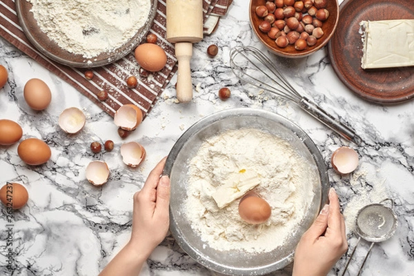 Fototapeta Close-up shot. Top view of a baker cook place, hands are working with a raw dough on the marble table background.