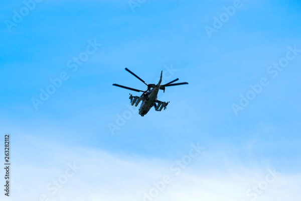 Obraz Russian military combat attack helicopter K-52 Alligator flies against a blue sky and clouds